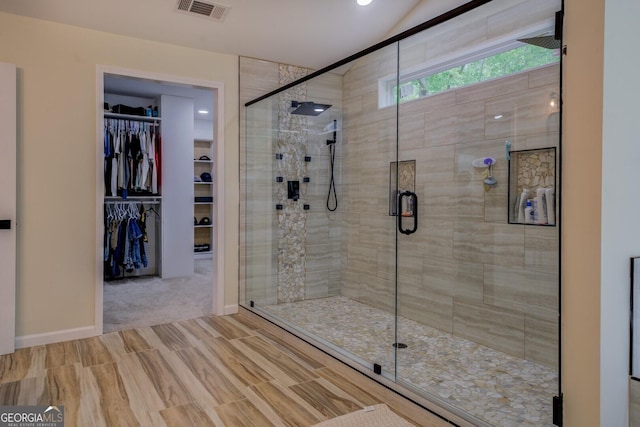 bathroom with visible vents, a shower stall, a walk in closet, and wood finished floors