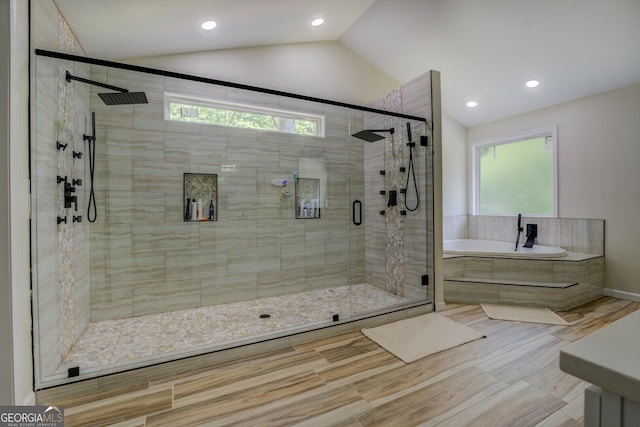 full bath featuring a stall shower, plenty of natural light, lofted ceiling, and a garden tub