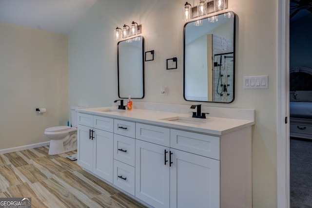 bathroom featuring a sink, a tile shower, toilet, and double vanity