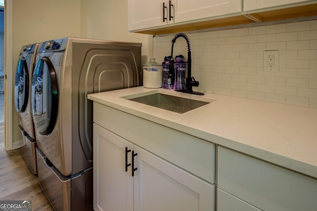 laundry room featuring separate washer and dryer, a sink, cabinet space, and wood finished floors