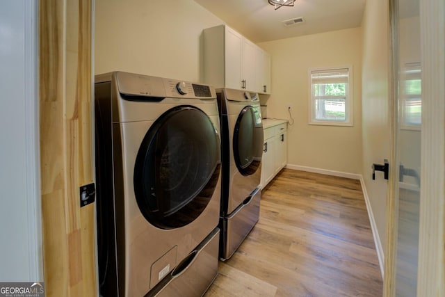 laundry area featuring cabinet space, light wood-style floors, baseboards, visible vents, and washing machine and dryer