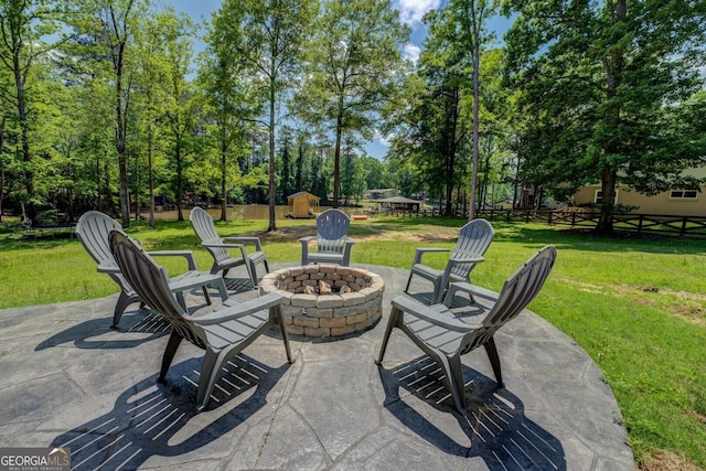 view of patio with fence, an outdoor structure, a fire pit, and a shed