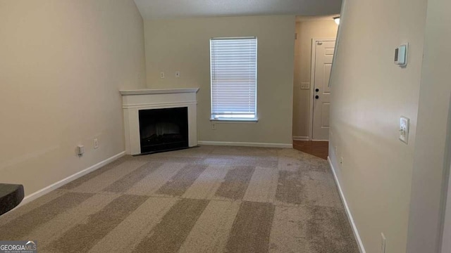 unfurnished living room with a fireplace, baseboards, and carpet floors