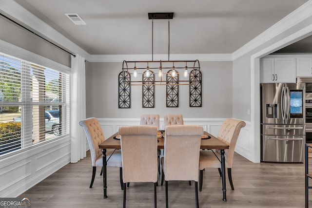 dining area featuring a decorative wall, visible vents, and ornamental molding