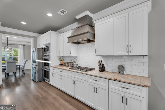 kitchen featuring crown molding, white cabinetry, visible vents, appliances with stainless steel finishes, and premium range hood