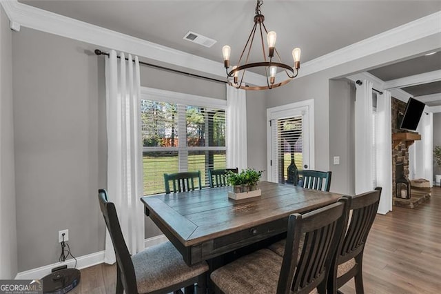 dining room featuring wood finished floors, a notable chandelier, ornamental molding, and visible vents
