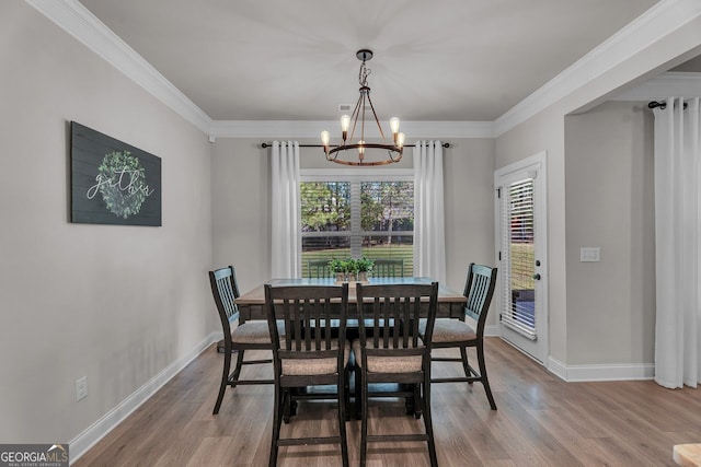 dining area featuring a notable chandelier, baseboards, crown molding, and wood finished floors