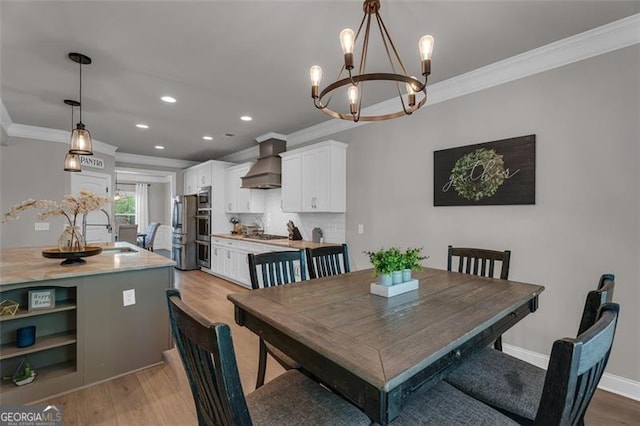 dining space with light wood-type flooring, ornamental molding, recessed lighting, a notable chandelier, and baseboards