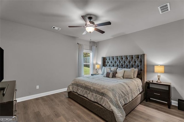 bedroom featuring visible vents, baseboards, ceiling fan, and wood finished floors