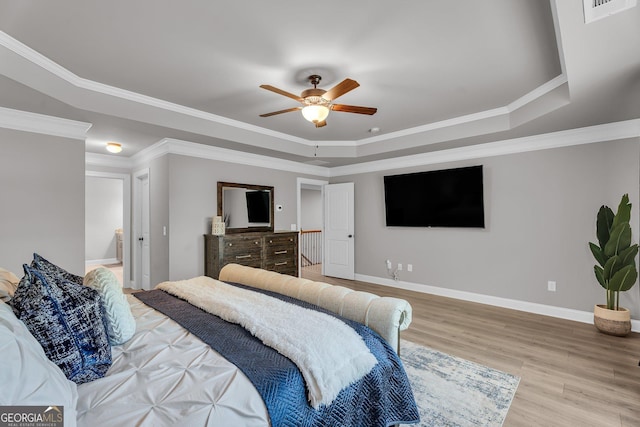 bedroom featuring baseboards, ceiling fan, crown molding, a tray ceiling, and wood finished floors