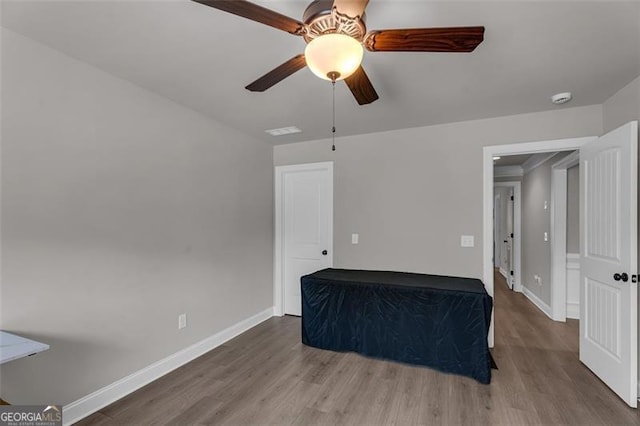 unfurnished room featuring wood finished floors, baseboards, and a ceiling fan