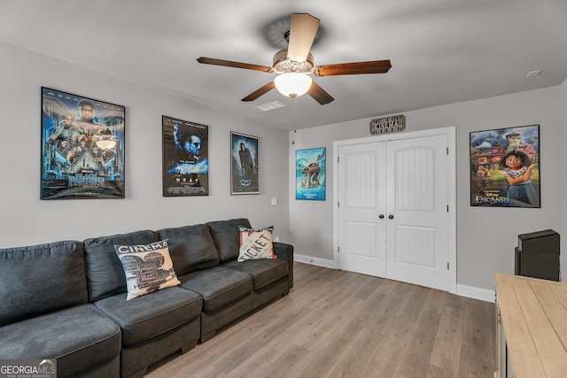 living room with visible vents, light wood-type flooring, a ceiling fan, and baseboards