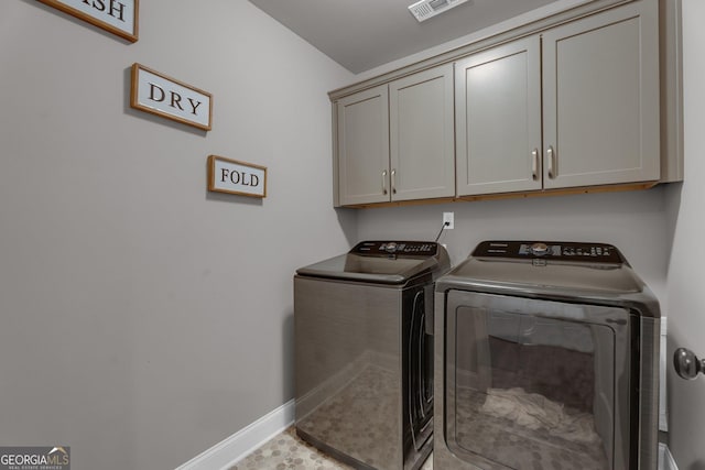 laundry room with washing machine and dryer, baseboards, visible vents, and cabinet space