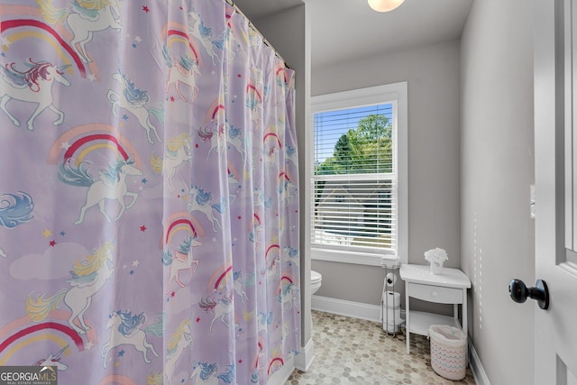 bathroom with baseboards, a shower with curtain, and toilet
