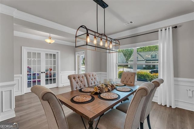 dining room featuring french doors, visible vents, and a wainscoted wall