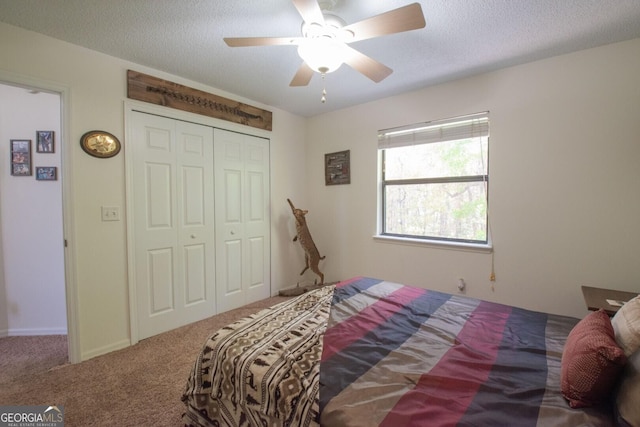 bedroom with a textured ceiling, a closet, a ceiling fan, and carpet