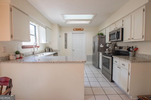 kitchen with a sink, light tile patterned floors, white cabinetry, and stainless steel appliances