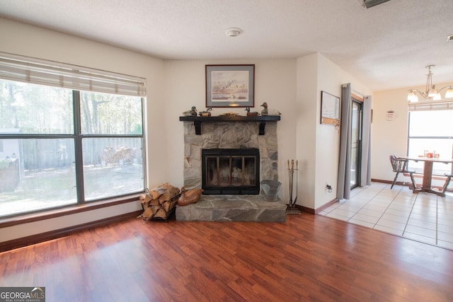living room with a textured ceiling, a chandelier, wood finished floors, and a healthy amount of sunlight