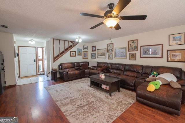 living area featuring visible vents, ceiling fan, wood finished floors, and stairs