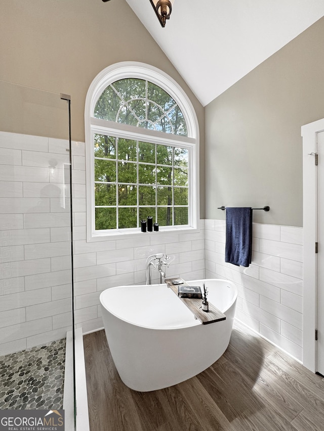 150 Fauna Meadows Dr, Newnan, GA 30263 - full bathroom with tile walls, a freestanding bath, vaulted ceiling, wood finished floors, and healthy amount of natural light