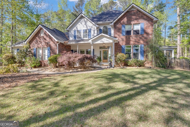 view of front of house with a front yard, brick siding, and fence