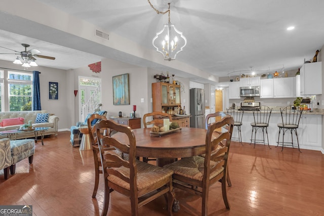 dining area featuring light wood-type flooring, visible vents, and ceiling fan with notable chandelier