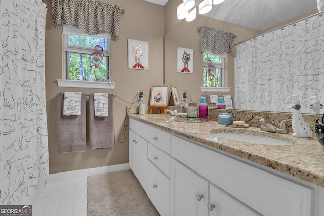 full bathroom featuring double vanity, a wealth of natural light, baseboards, and a sink