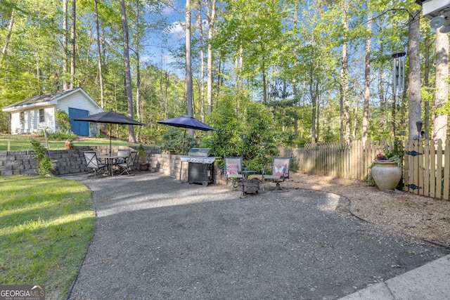 view of patio featuring outdoor dining space, an outdoor fire pit, fence, area for grilling, and an outdoor structure