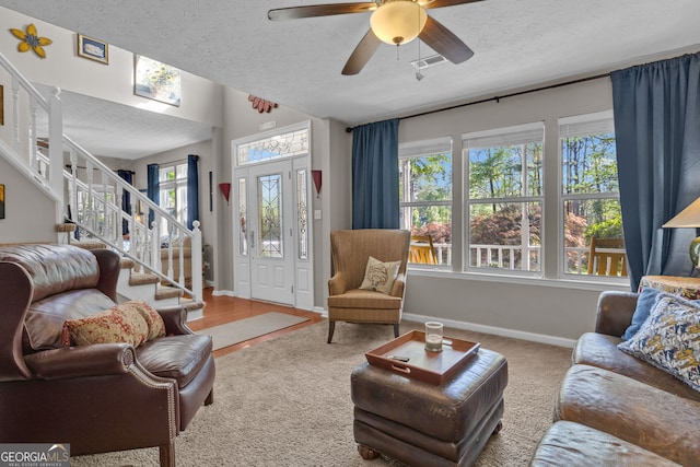 living room with carpet flooring, a textured ceiling, stairway, baseboards, and ceiling fan