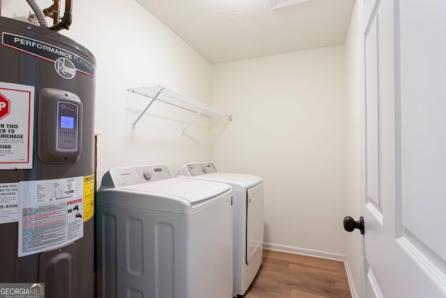 laundry room featuring laundry area, separate washer and dryer, water heater, wood finished floors, and baseboards