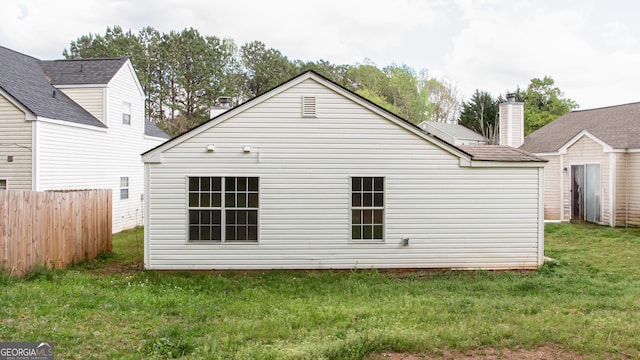 back of property with a yard, fence, and a chimney