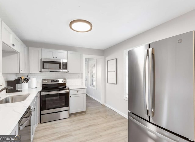 1340 Hawthorne Ave SE, Smyrna, GA 30080 - kitchen featuring appliances with stainless steel finishes, light stone counters, a sink, decorative backsplash, and baseboards