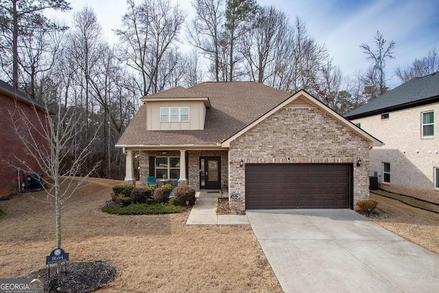 view of front of home with a garage, brick siding, a shingled roof, concrete driveway, and a porch
