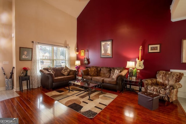 living room featuring baseboards, wood finished floors, and high vaulted ceiling