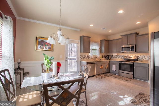 dining space with crown molding, wainscoting, a chandelier, light wood-style flooring, and recessed lighting
