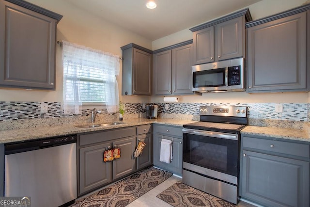 kitchen featuring a sink, appliances with stainless steel finishes, gray cabinets, and backsplash