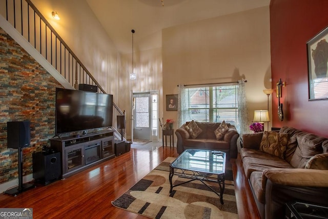 living room featuring wood finished floors, high vaulted ceiling, and stairway
