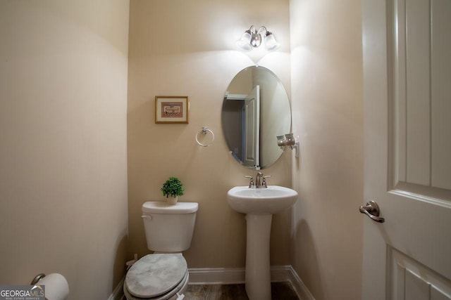 half bathroom with baseboards, a sink, and toilet