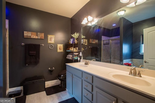 bathroom with double vanity, a sink, a tile shower, and toilet