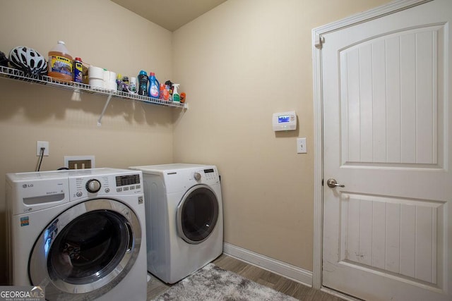 washroom with separate washer and dryer, laundry area, baseboards, and wood finished floors