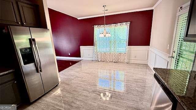 unfurnished dining area featuring crown molding, an inviting chandelier, wainscoting, and a wealth of natural light