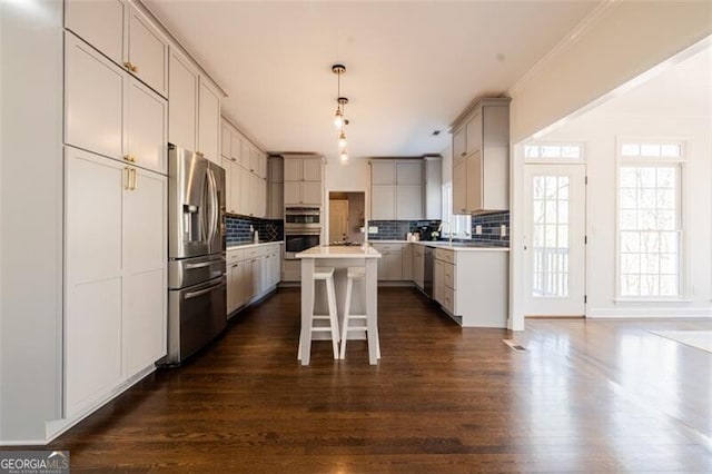 kitchen with stainless steel appliances, backsplash, dark wood-style floors, and a center island