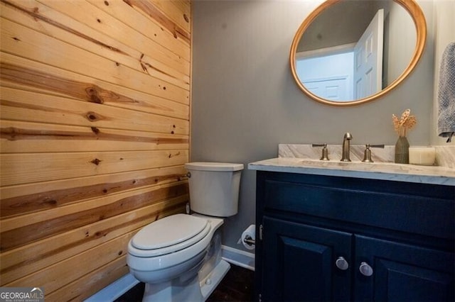 half bath with baseboards, vanity, and toilet