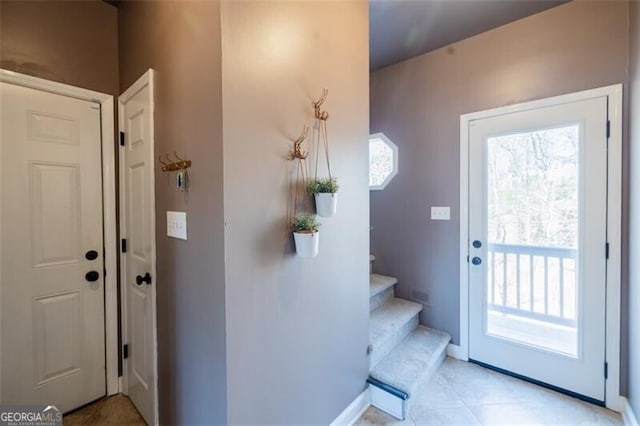 entryway featuring plenty of natural light, stairs, baseboards, and light tile patterned flooring