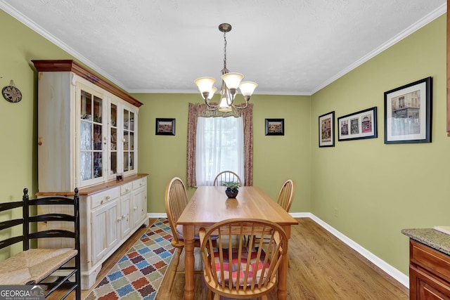 dining area featuring wood finished floors, a chandelier, baseboards, and ornamental molding