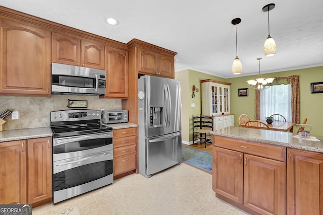 kitchen with stainless steel appliances, brown cabinetry, tasteful backsplash, a chandelier, and pendant lighting
