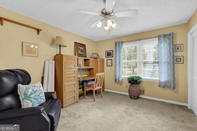 sitting room featuring ceiling fan, light colored carpet, a textured ceiling, and baseboards