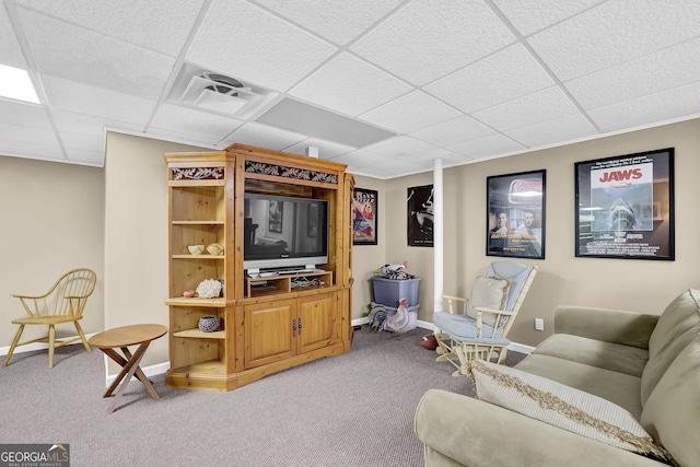 carpeted living area featuring a drop ceiling and baseboards