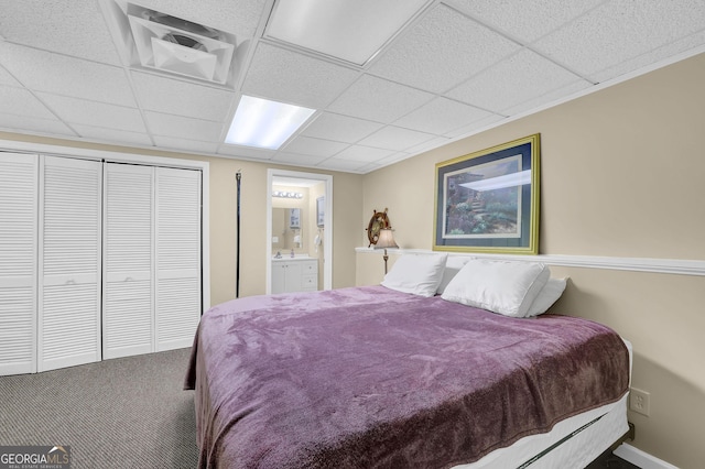 carpeted bedroom featuring a paneled ceiling, a closet, and connected bathroom