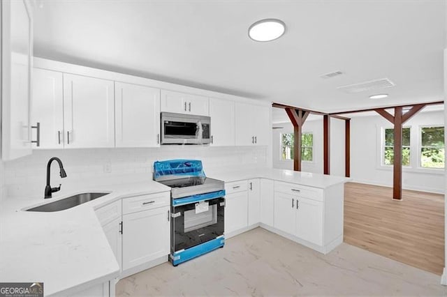 kitchen with stainless steel microwave, tasteful backsplash, a peninsula, range with electric cooktop, and a sink